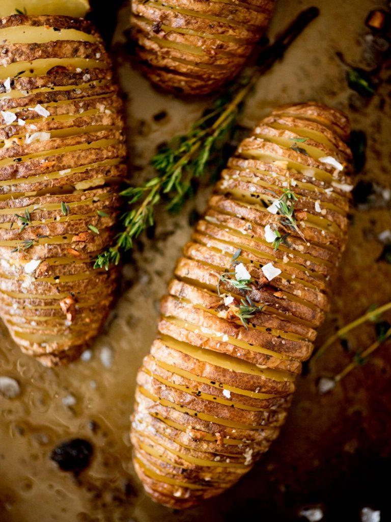Patate Hasselback all'Aglio 2 patate hasselback al burro e aglio guarnite con timo fresco e sale in fiocchi