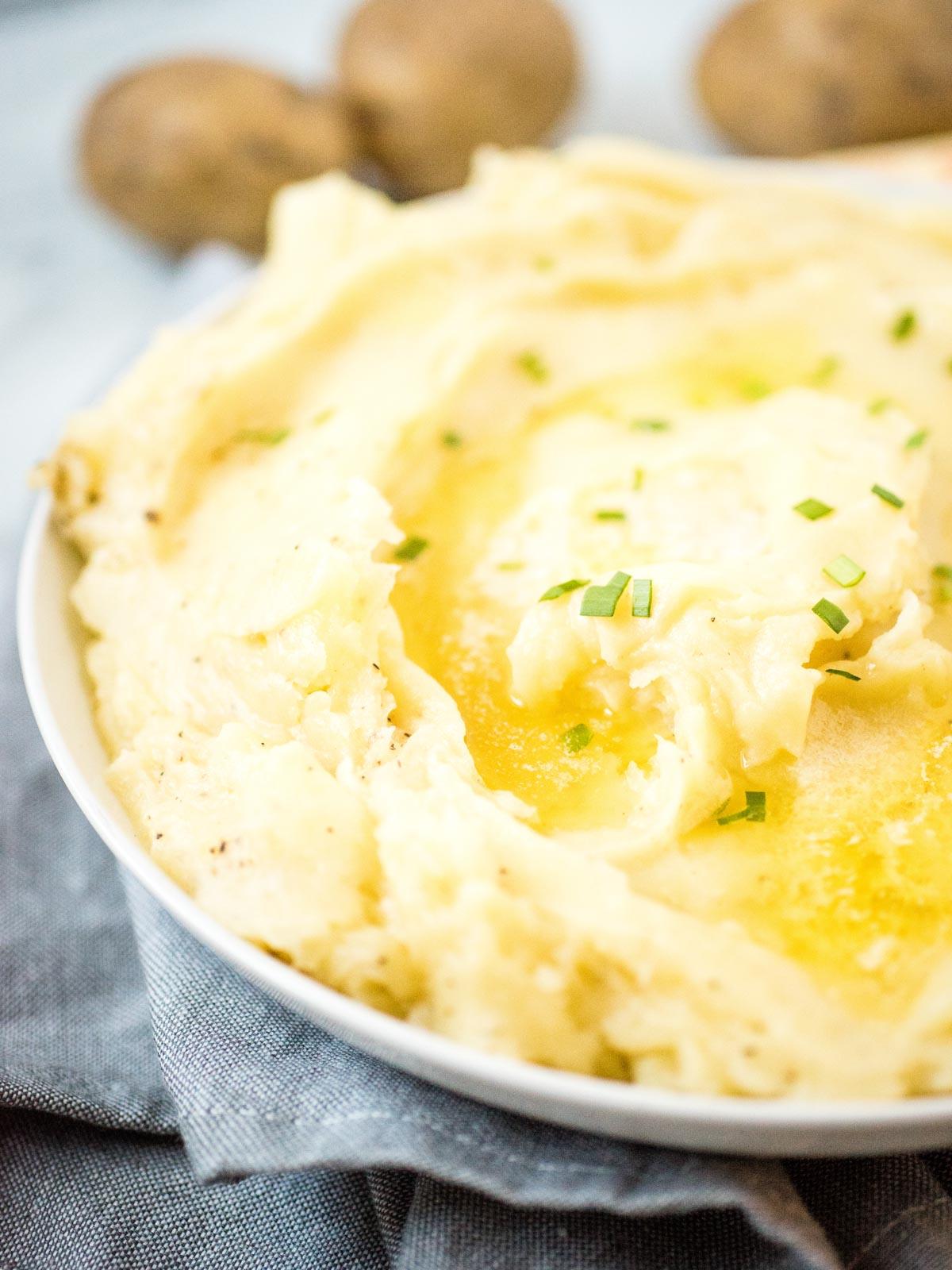 Purè di Patate nella Instant Pot alla Perfezione 2 purè di patate in un piatto bianco guarnito con burro fuso