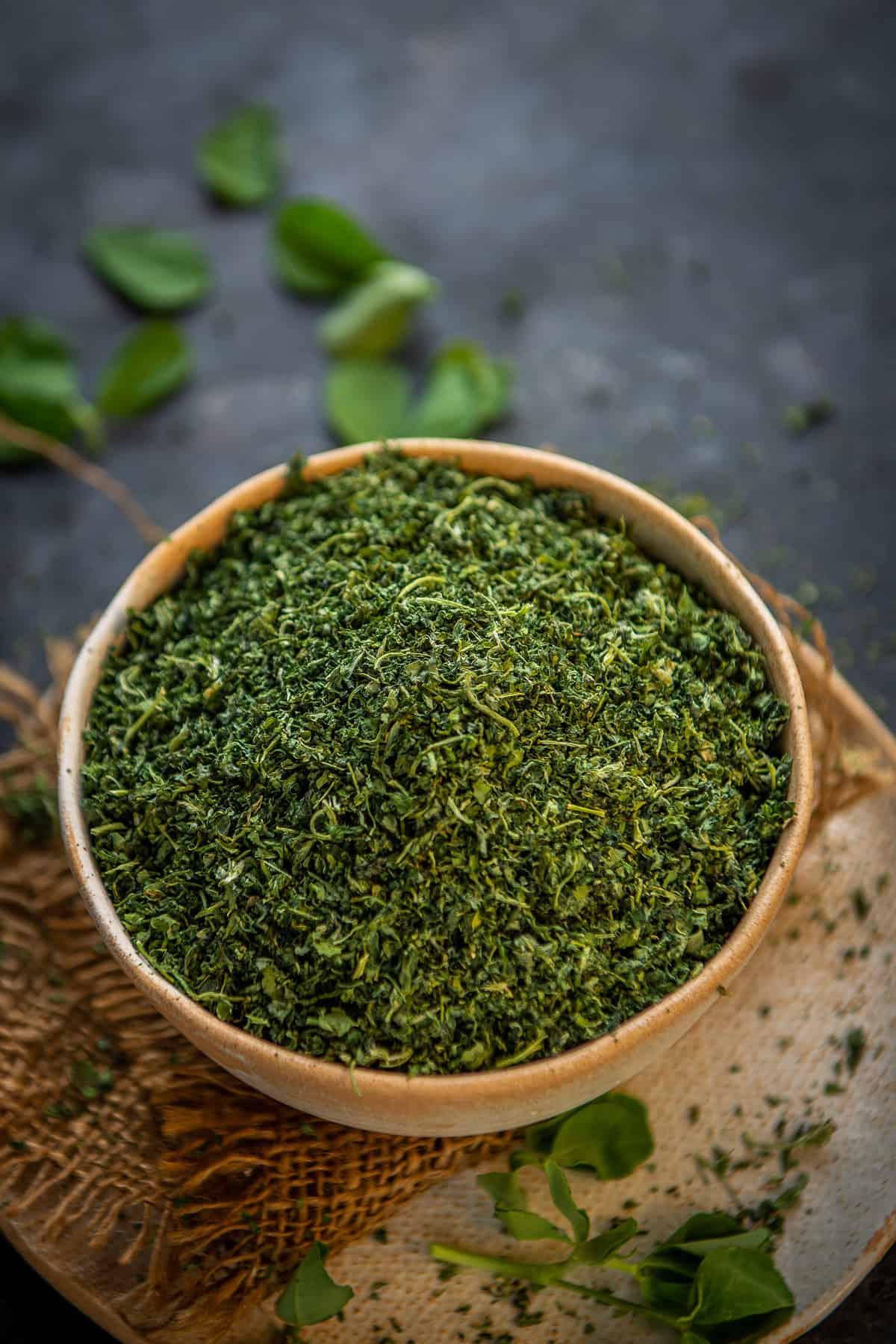 Ciotola di foglie di fieno greco essiccate (Kasuri Methi) fatte in casa, pronte per l'uso.