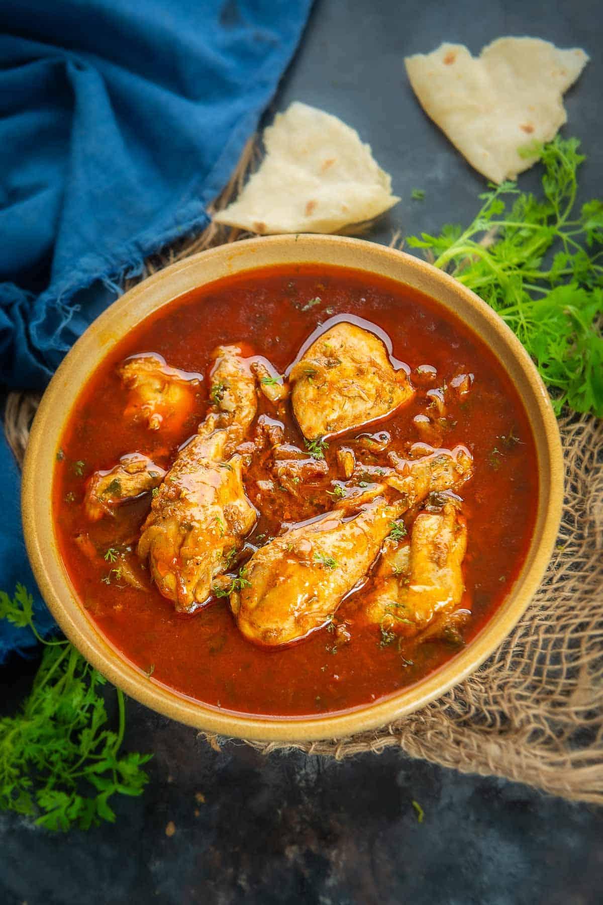 Curry di pollo al pomodoro servito in una ciotola, con un tocco di coriandolo fresco.