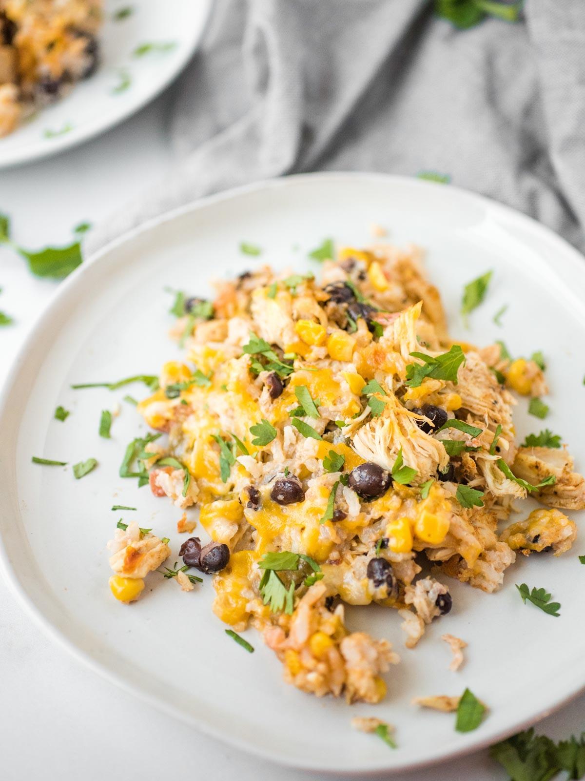 Sformato di Pollo Tex-Mex, Fagioli Neri e Riso 2 Piatto bianco con una porzione abbondante di teglia di pollo Tex-Mex, mostrando il riso, il pollo e i fagioli neri.