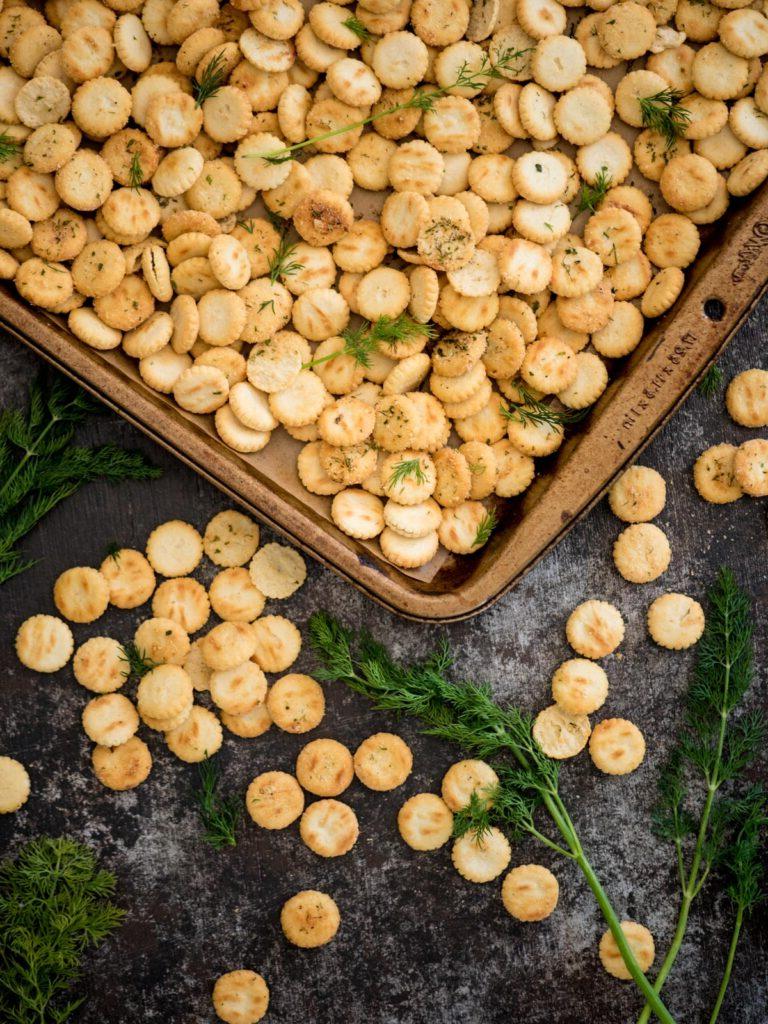 Teglia da forno coperta di cracker alle ostriche conditi con rametti di aneto fresco.
