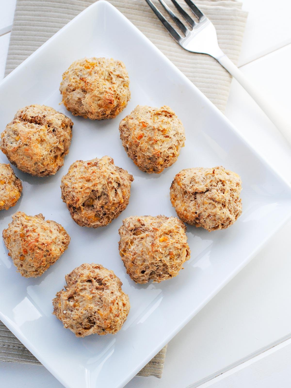 **Ricetta di Polpette di Salsiccia con Bisquick** 2 Polpette di salsiccia leggere su un piatto bianco.