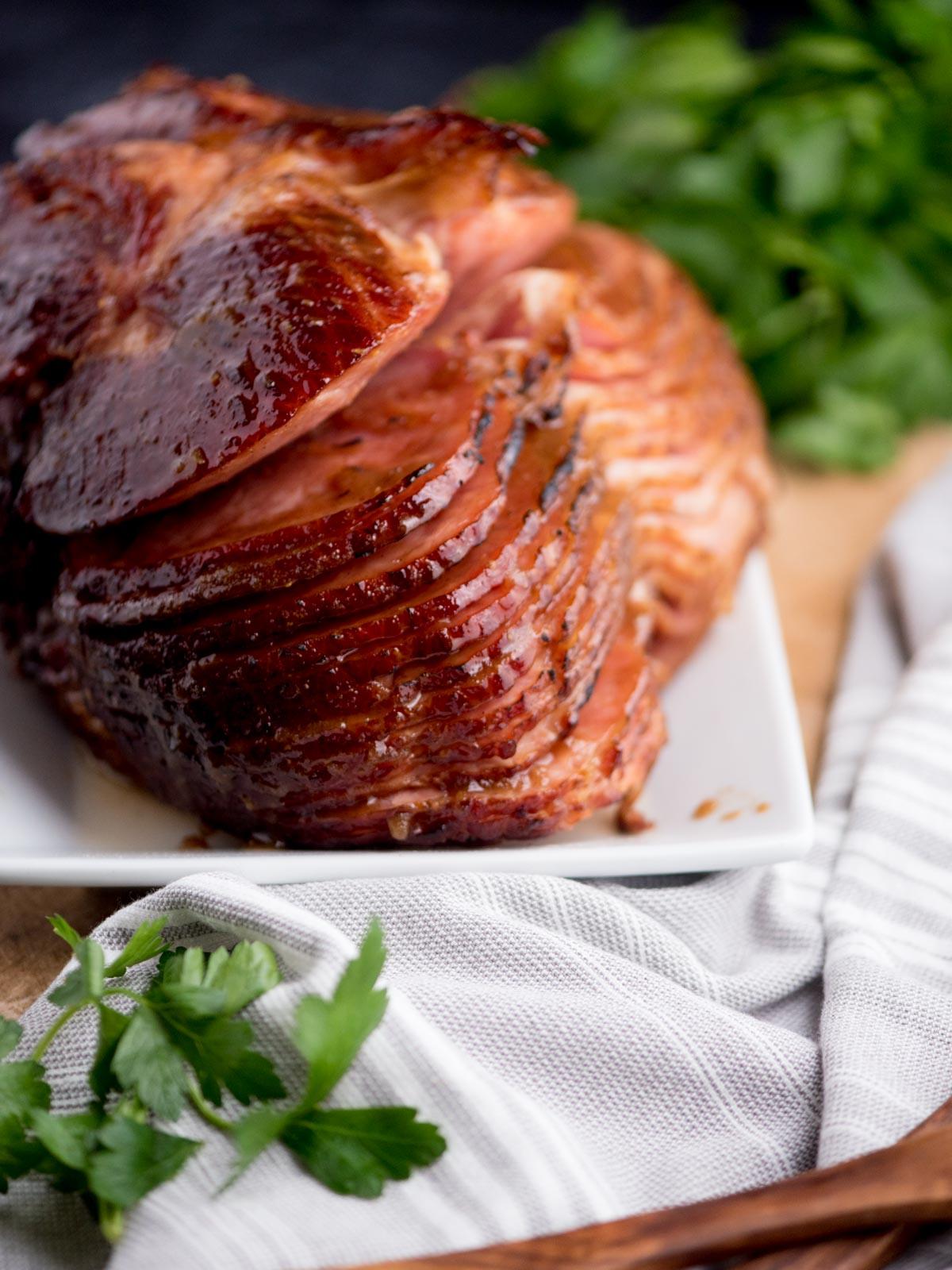 Prosciutto Glassato con Zucchero di Canna 2 Prosciutto glassato con zucchero di canna su un piatto, circondato da un canovaccio da cucina e prezzemolo