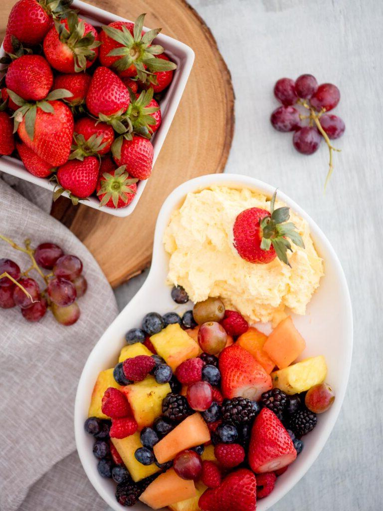 Crema allo Yogurt e Formaggio Spalmabile per Frutta 2 Crema dip allo yogurt con una ciotola di frutta e un contenitore di fragole fresche