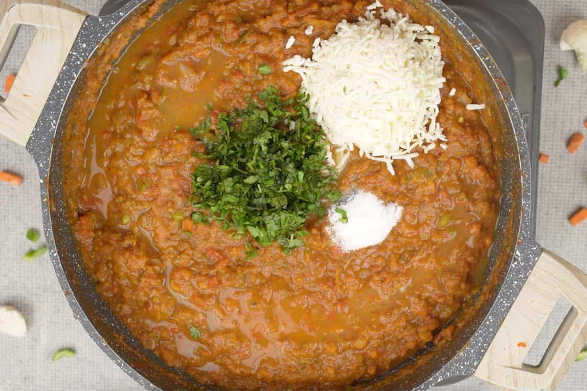 Paneer, succo di lime, sale e coriandolo aggiunti alla padella, mescolati nel bhaji.