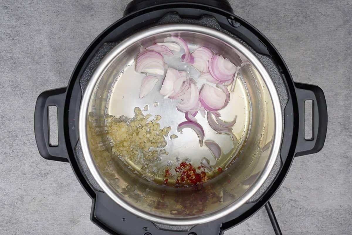 Instant Pot Pad Thai Vegetariano 11 Aglio, peperoncino rosso e cipolla aggiunti all'olio caldo nella pentola istantanea.