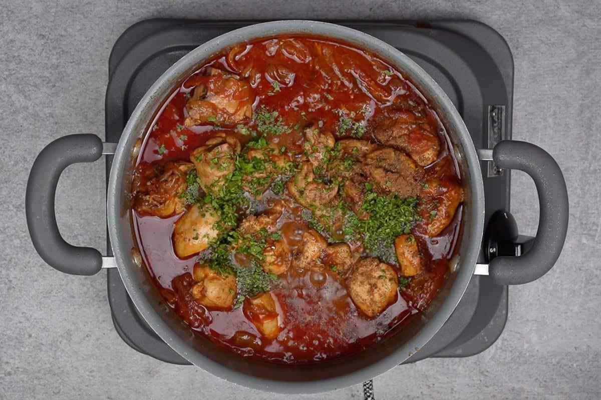 Curry di pollo al pomodoro pronto, fumante e guarnito con coriandolo.