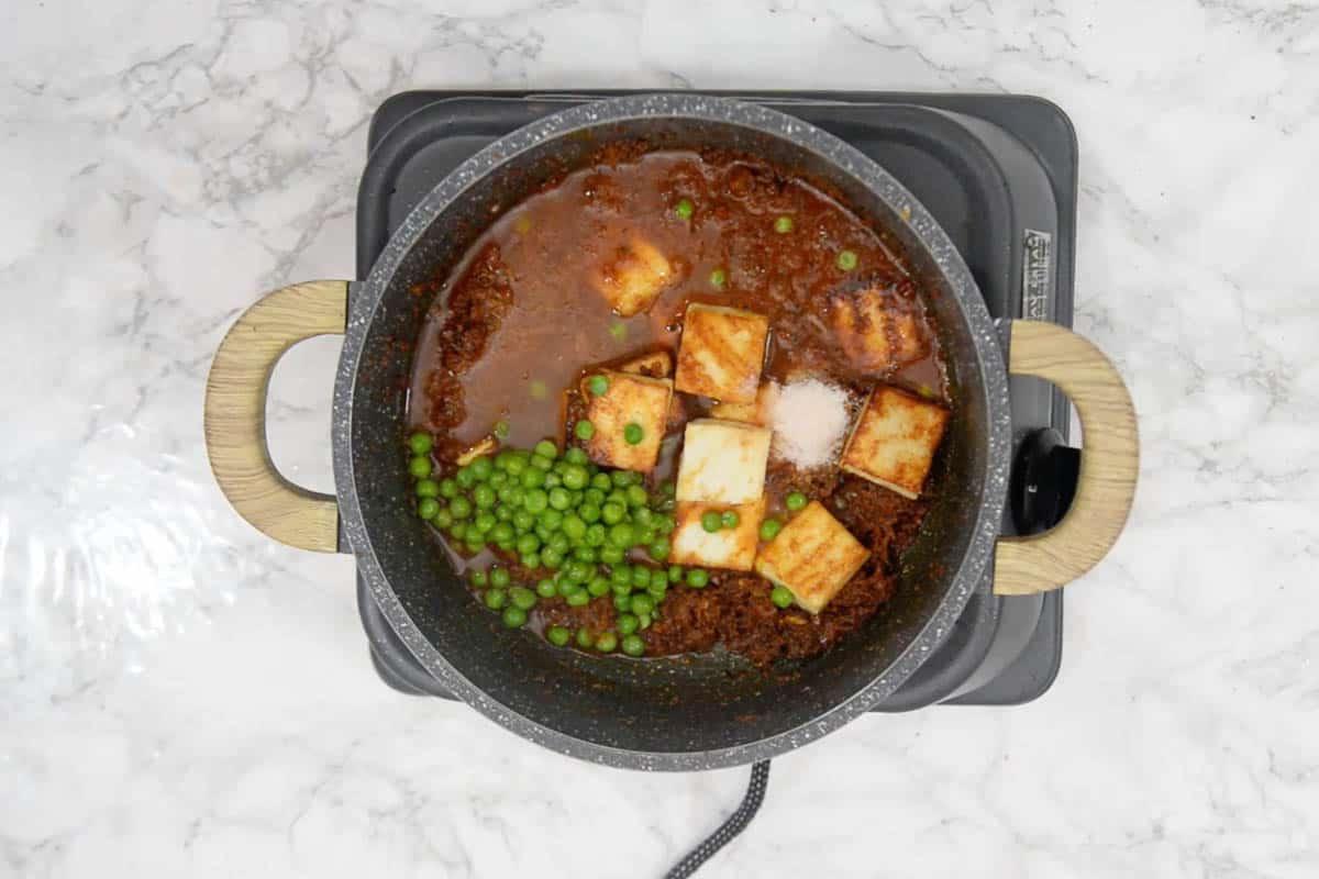Curry di Matar Paneer in Stile Dhaba 11 Cubetti di paneer e piselli aggiunti alla padella con il sugo speziato, pronti per essere mescolati.