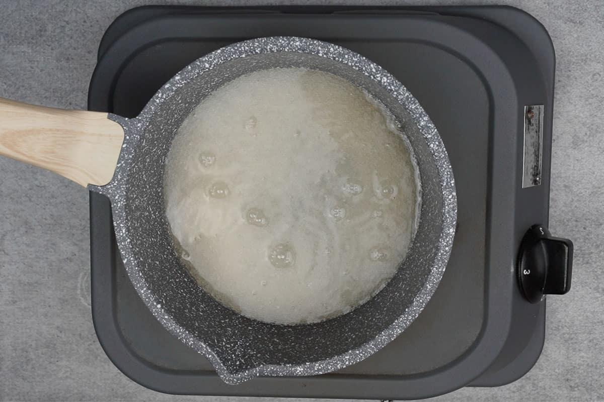 Dolce di pane 12 Zucchero e acqua aggiunti in una casseruola.