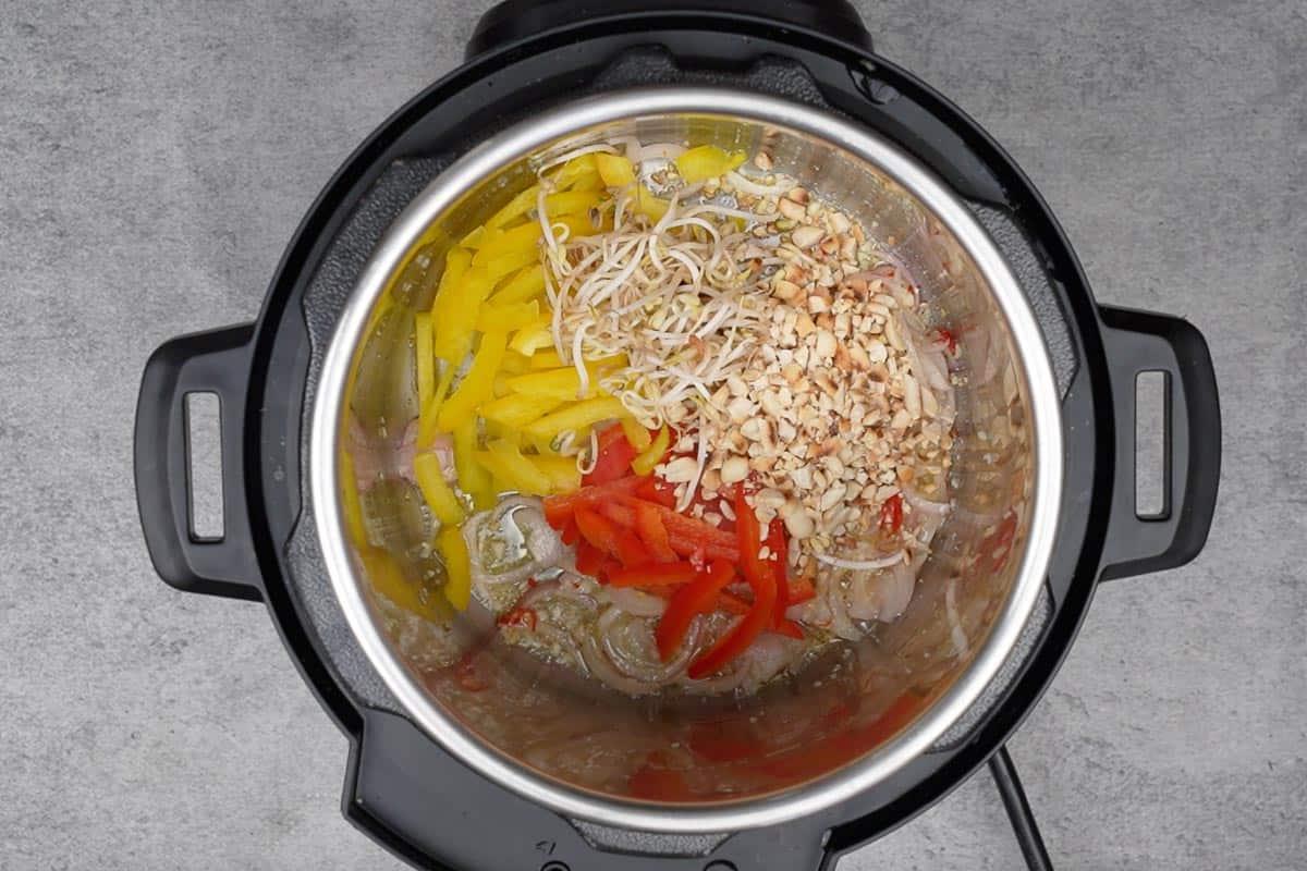 Instant Pot Pad Thai Vegetariano 12 Peperoni, germogli di soia e arachidi aggiunti alla pentola.