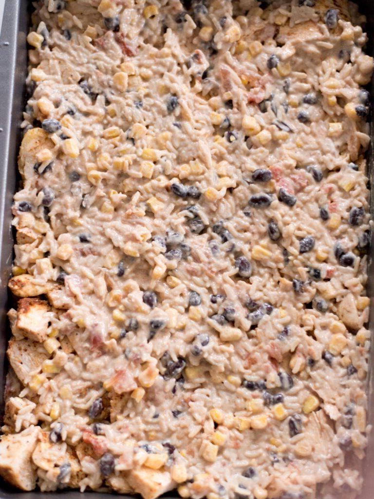 Sformato di Pollo Tex-Mex, Fagioli Neri e Riso 13 Ultimo strato di miscela di riso e verdure aggiunto sopra il pollo condito nella pirofila, completando la base della teglia.