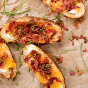 Facili Bucce di Patate in Friggitrice ad Aria 13 Bucce di patate ripiene con panna acida, pancetta e formaggio, guarnite con erba cipollina tritata, pronte da servire.