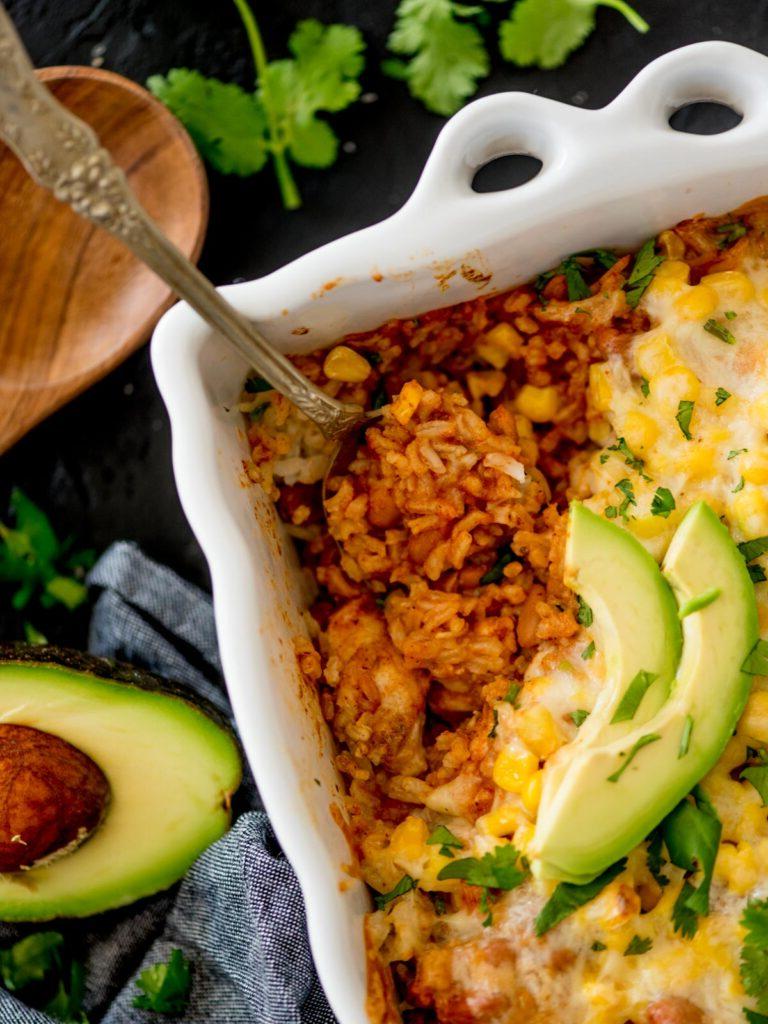 casseruola di riso messicana guarnita con coriandolo e avocado su un tavolo di legno