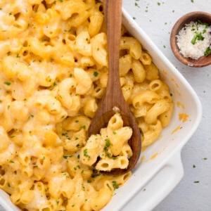**I Migliori Maccheroni al Forno Super Formaggiosi** 14 Una paletta di Mac and Cheese prelevata da una teglia, con un cucchiaio di legno appoggiato.