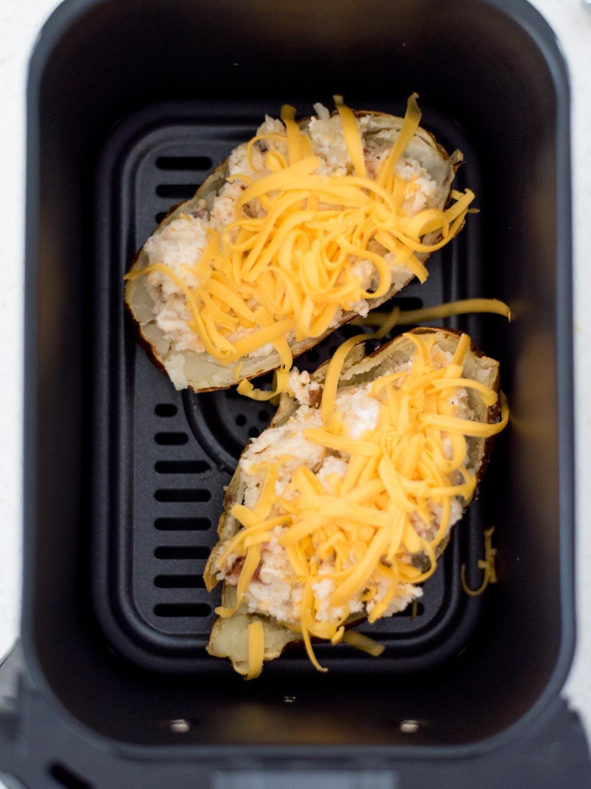 Patate Doppia Cottura in Friggitrice ad Aria 18 Due patate ripiene guarnite con formaggio grattugiato nel forno ad aria pronte per essere cotte.