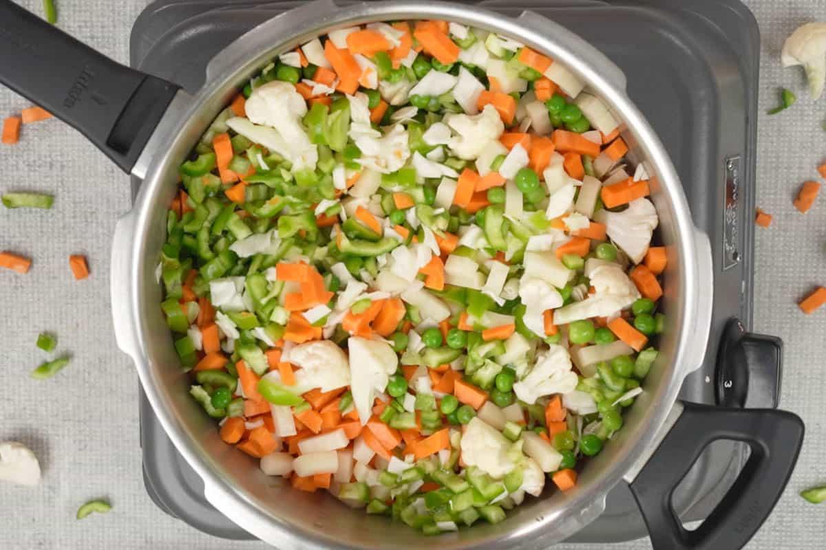 Verdure e acqua aggiunte a una pentola a pressione, pronte per la cottura.