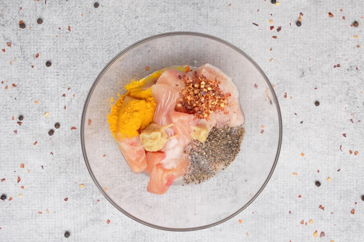 Pesce e ingredienti per la marinatura aggiunti in una ciotola.