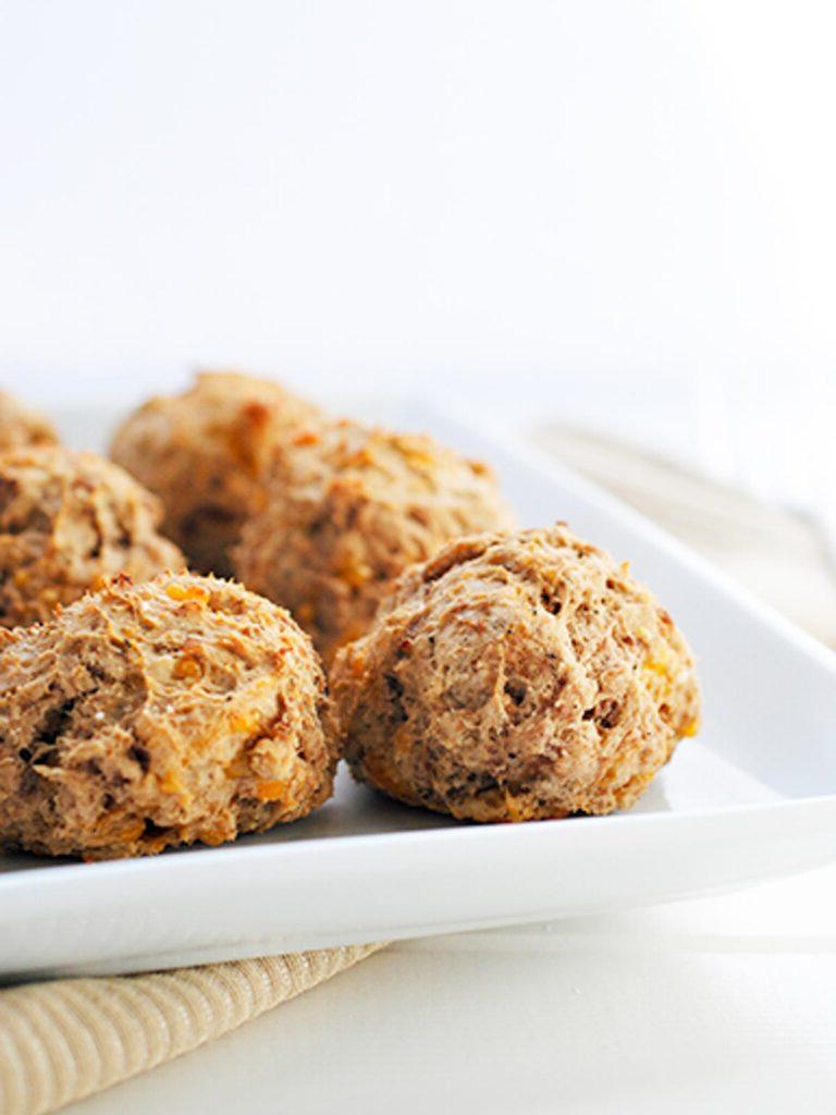 **Ricetta di Polpette di Salsiccia con Bisquick** 3 Vista laterale di polpette di salsiccia leggere su un piatto da portata bianco.