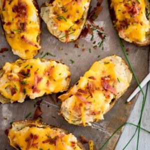 Patate Doppia Cottura in Friggitrice ad Aria 21 Patate ripiene guarnite con pancetta extra su una teglia da forno.