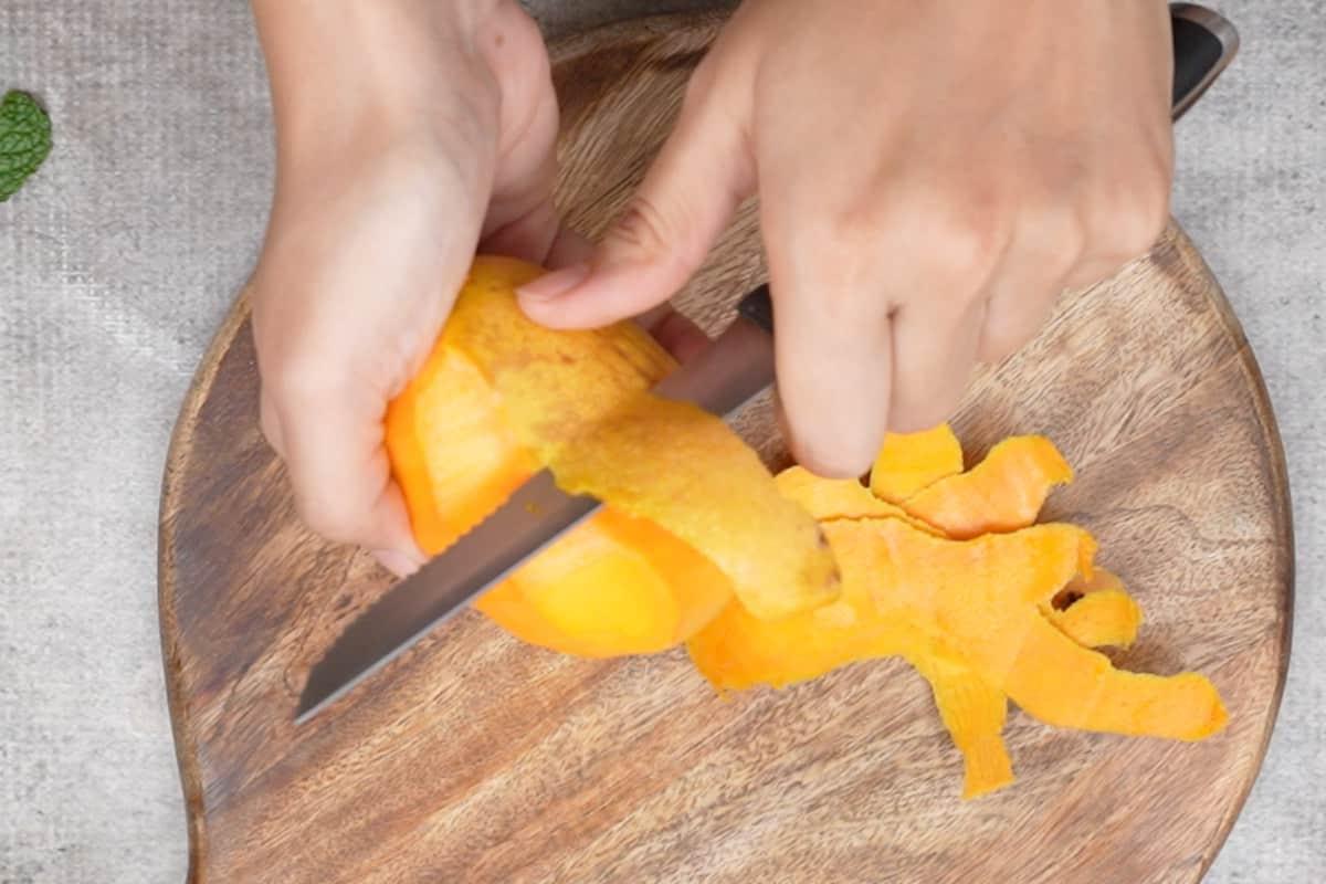 Aamras 4 Pelare il mango con un coltello in preparazione per la purea.