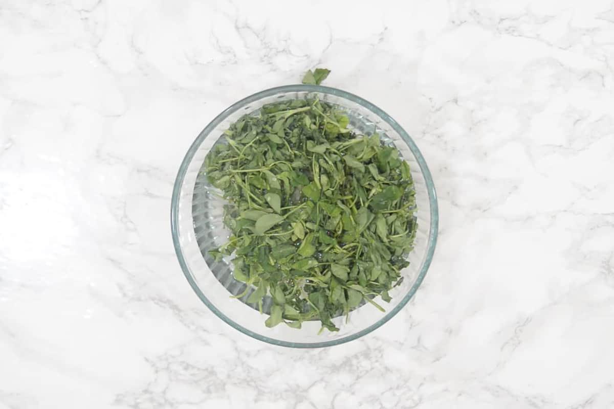 Foglie di methi in fase di lavaggio meticoloso in acqua per rimuovere le impurità.