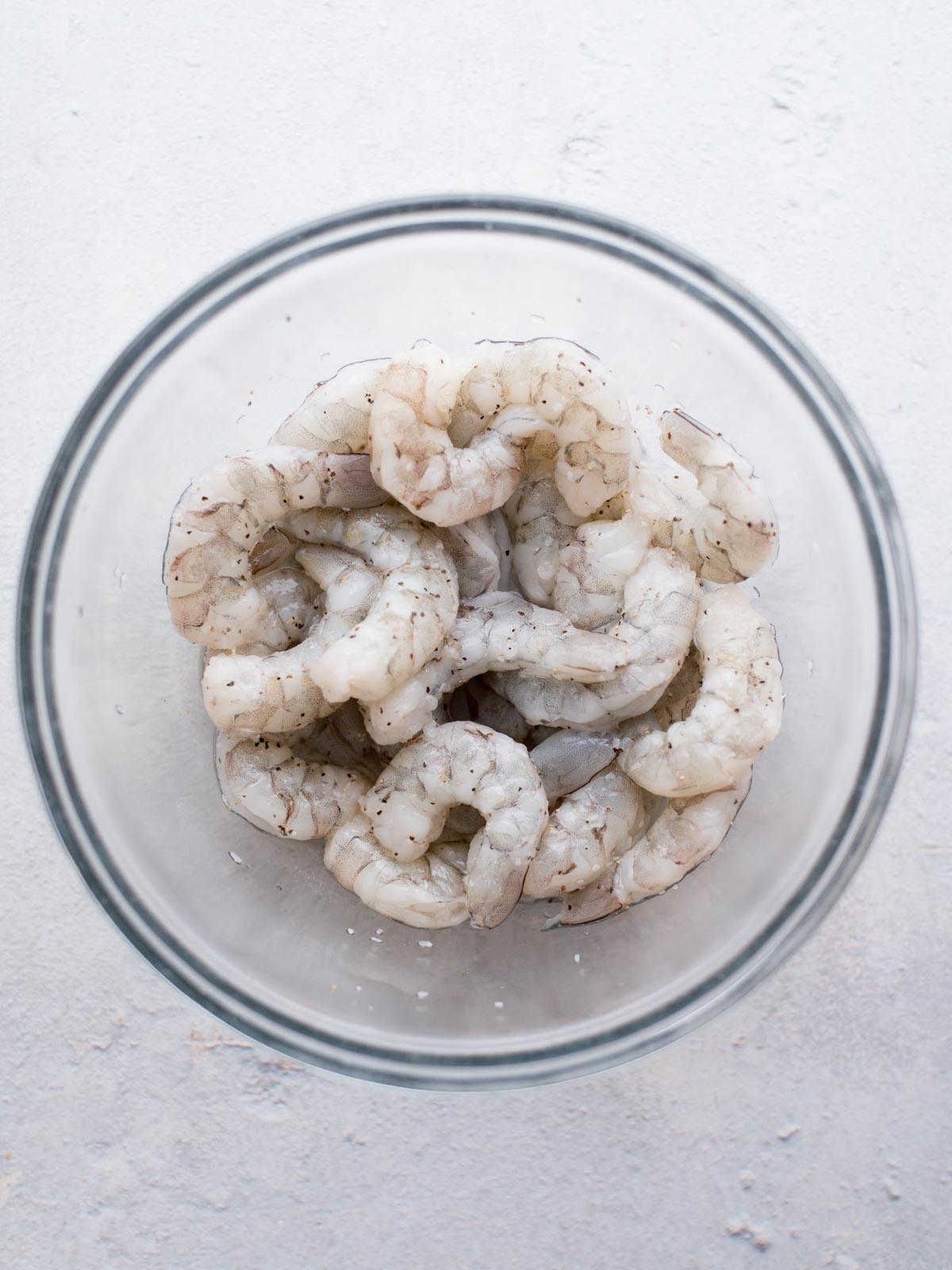 Riso fritto con gamberetti facile 4 Gamberi in una ciotola di vetro conditi con sale e pepe