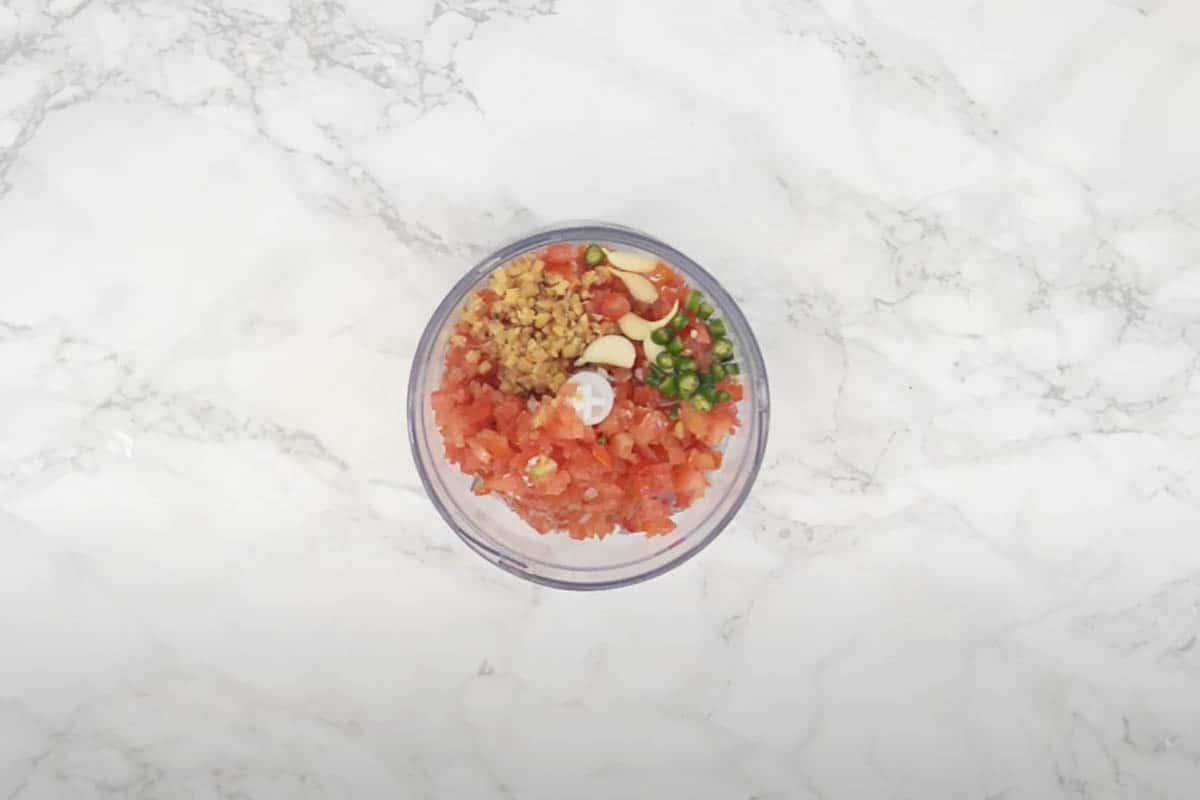 Curry di Matar Paneer in Stile Dhaba 4 Cipolla, pomodoro, zenzero, aglio e peperoncino verde aggiunti al frullatore per la pasta di masala, pronti per essere frullati.