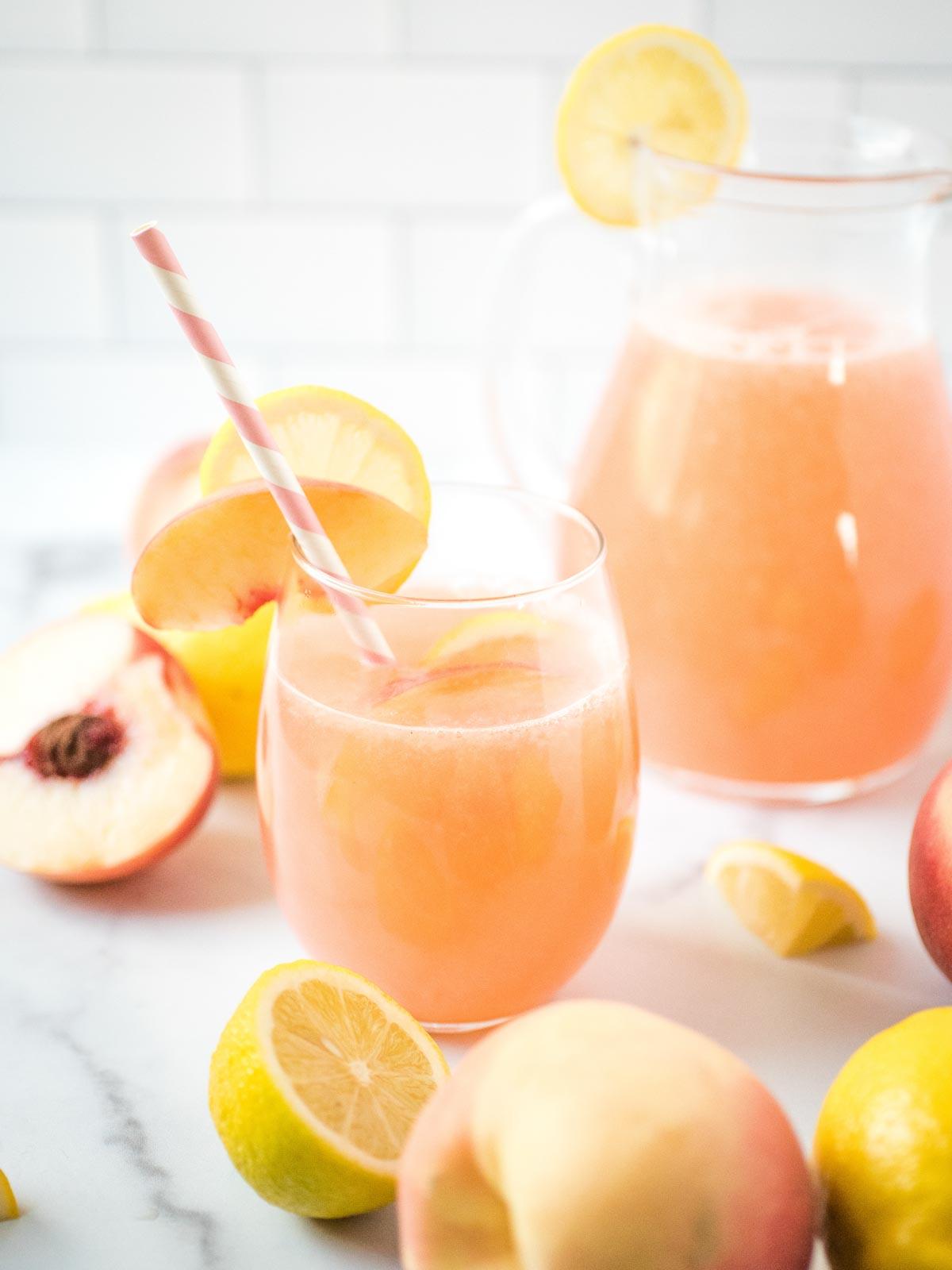Come fare la Limonata alla Pesca Fatta in Casa 4 Un bicchiere di limonata alla pesca davanti alla brocca con pesche e limoni sul bancone
