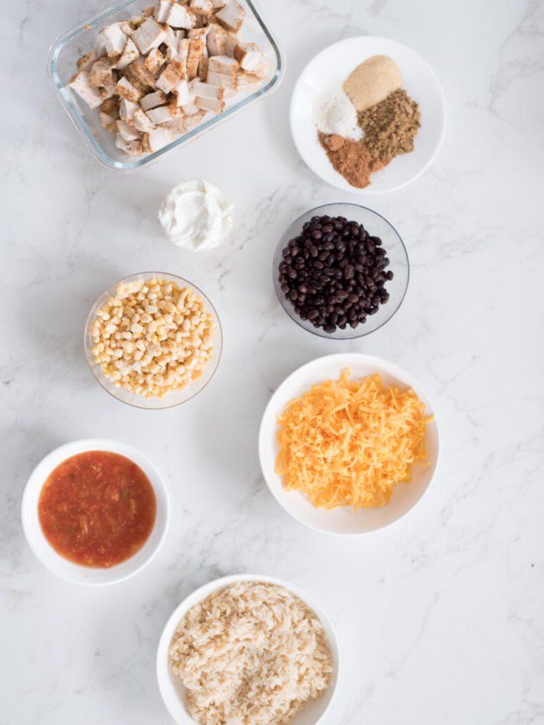 Sformato di Pollo Tex-Mex, Fagioli Neri e Riso 4 Ingredienti disposti su un tavolo, inclusi il pollo sfilacciato, il riso, i fagioli neri, il mais e le spezie, pronti per essere utilizzati nella teglia di pollo Tex-Mex.