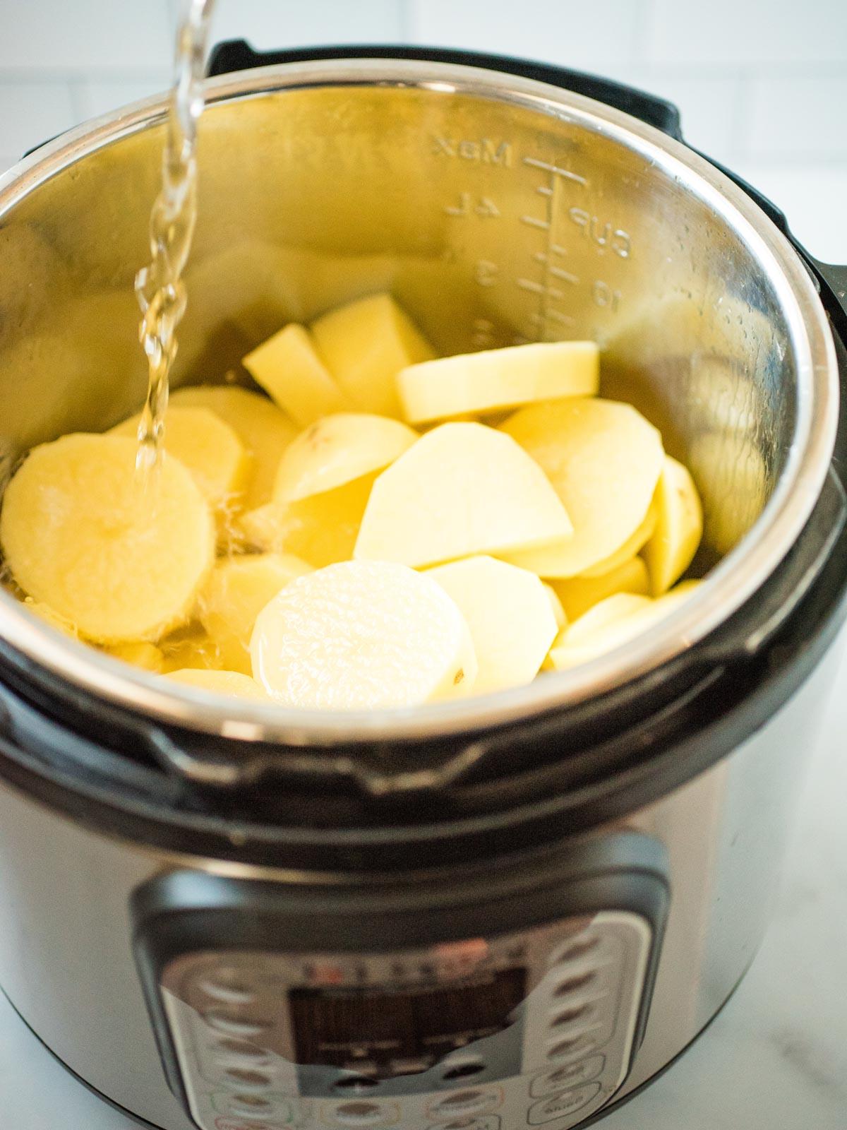 Purè di Patate nella Instant Pot alla Perfezione 5 patate affettate in un instant pot con acqua che vi scorre sopra