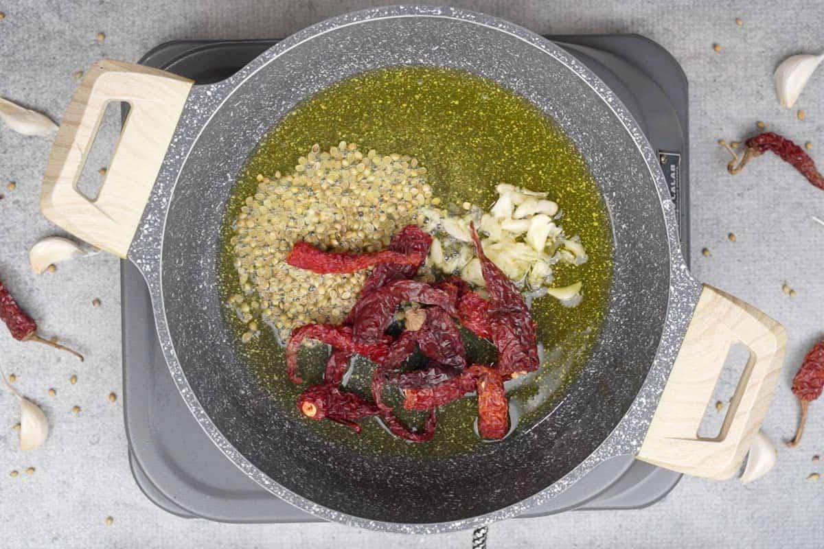 Semi di coriandolo, aglio e peperoncini aggiunti alla padella.