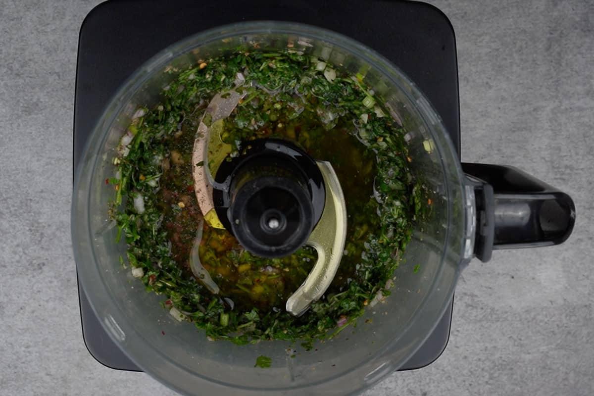 Olio d'oliva restante e aceto di vino rosso aggiunti al robot da cucina.