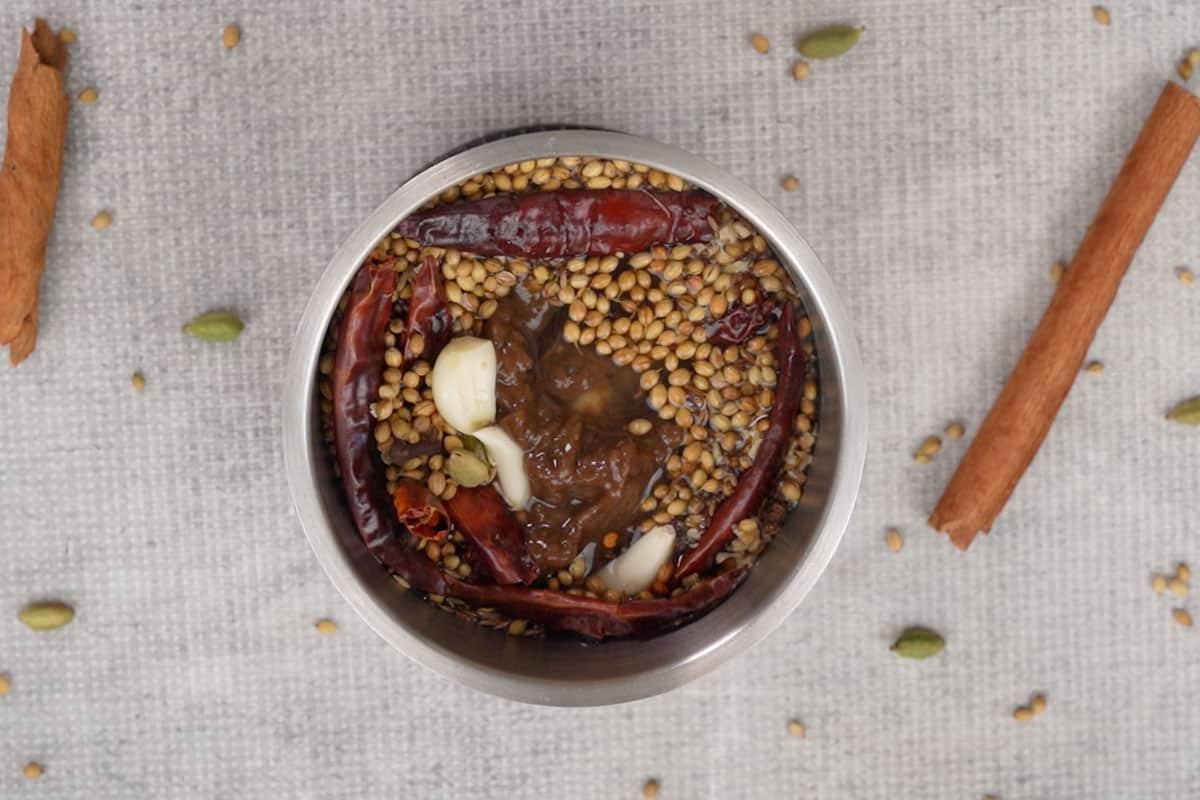 Ingredienti tostati aggiunti a un frullatore insieme ad aglio, zenzero, pasta di tamarindo e acqua.