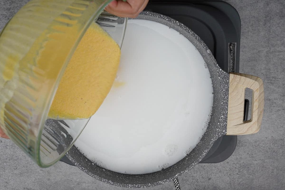 Porridge Giamaicano di Mais 5 La miscela di farina di mais viene aggiunta gradualmente alla pentola con i liquidi caldi, mescolando continuamente.