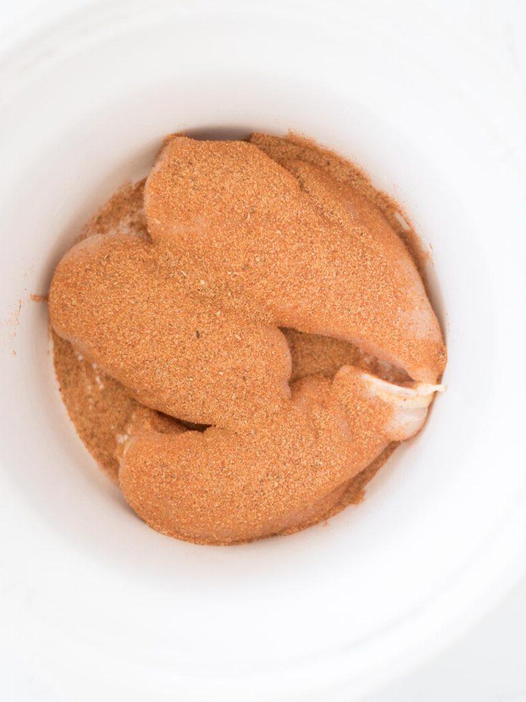 Pollo Messicano a Cottura Lenta 5 Condimento per taco cosparso sui petti di pollo crudi nella slow cooker.