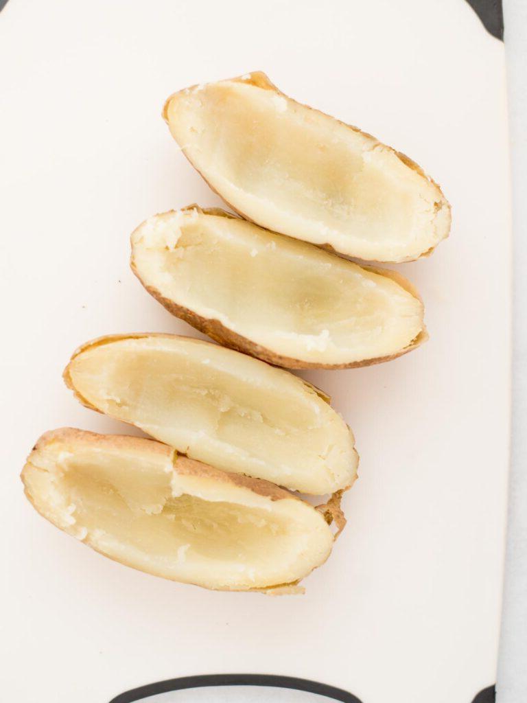 Facili Bucce di Patate in Friggitrice ad Aria 5 4 patate russet svuotate e pronte per essere preparate su carta forno.