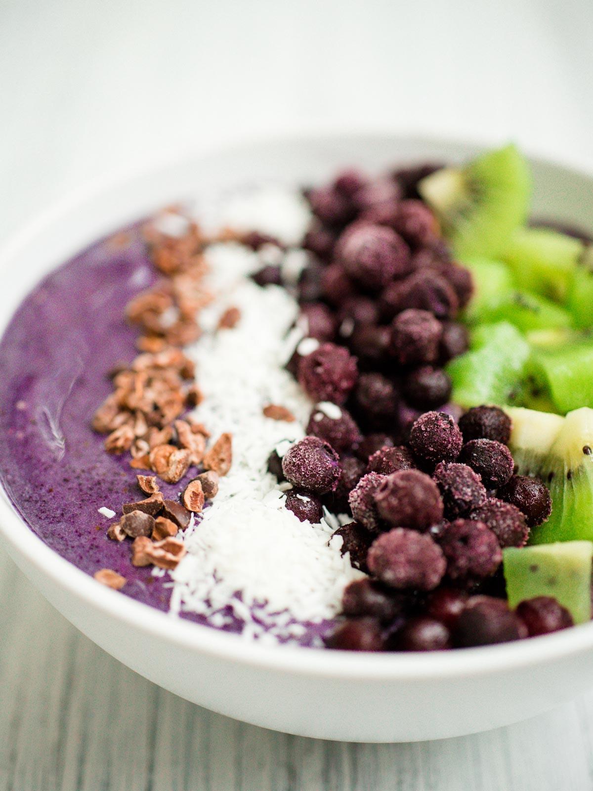 Smoothie Bowl Mirtillo e Banana 5 Smoothie bowl ai mirtilli e banane in una ciotola bianca con guarnizioni