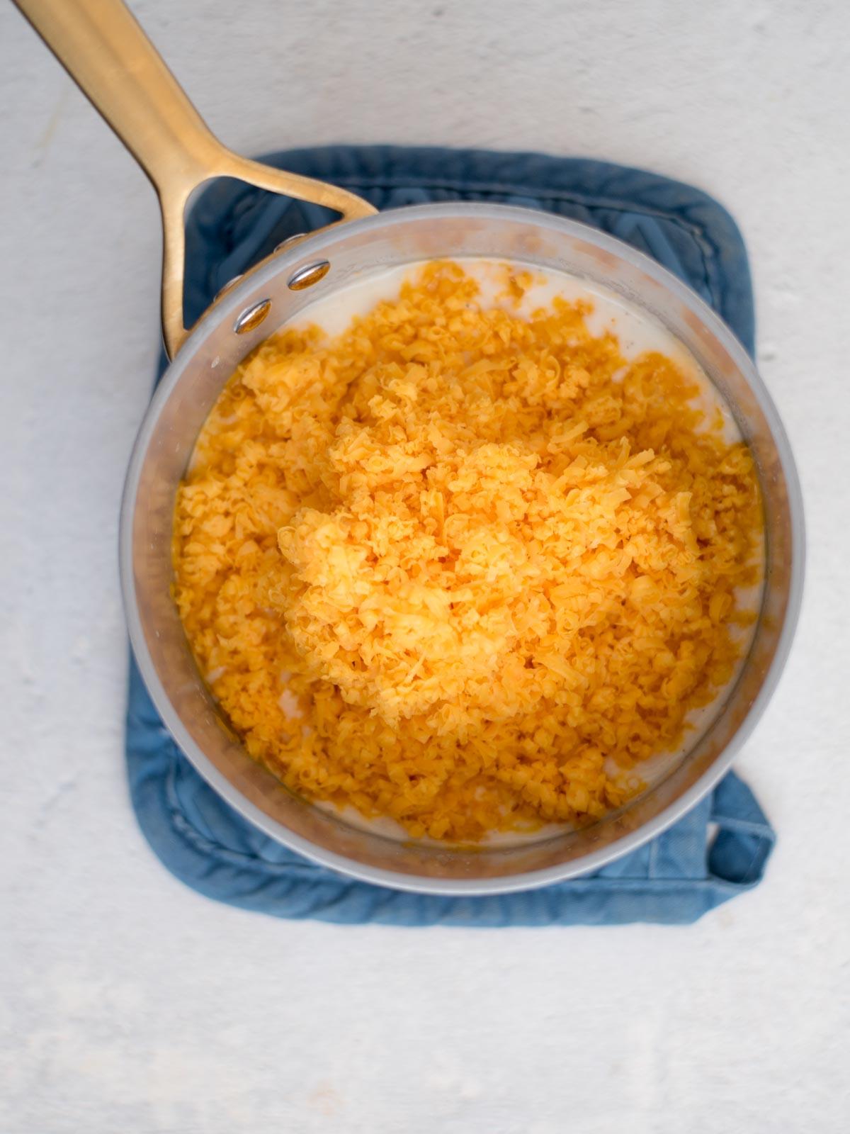 **I Migliori Maccheroni al Forno Super Formaggiosi** 5 Formaggio grattugiato aggiunto a una casseruola con la salsa base.
