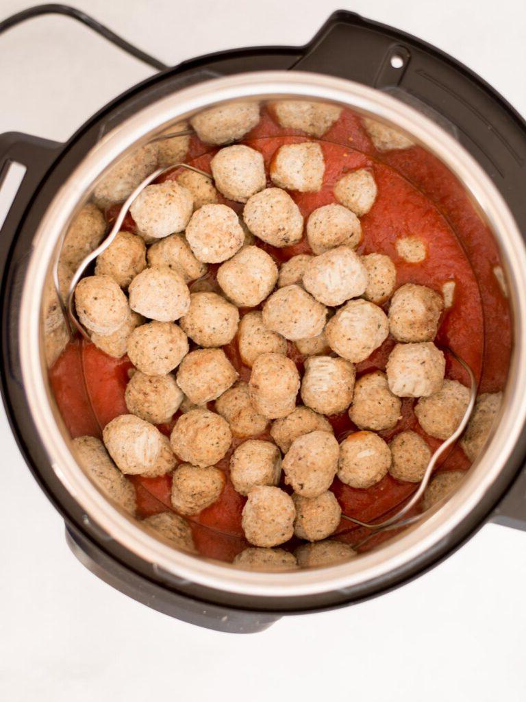 Polpette surgelate su salsa di pomodoro in una pentola istantanea pronta per la cottura.
