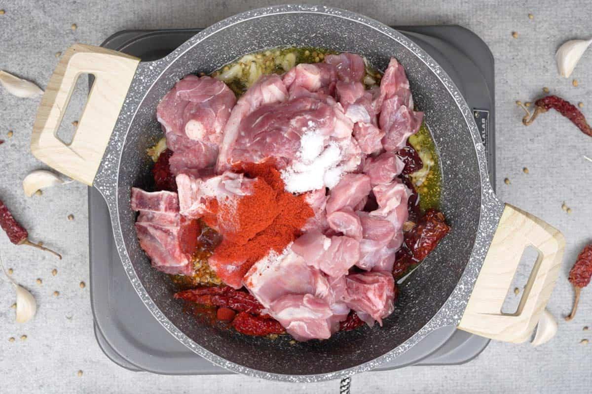Montone, sale e polvere di peperoncino aggiunti alla padella.