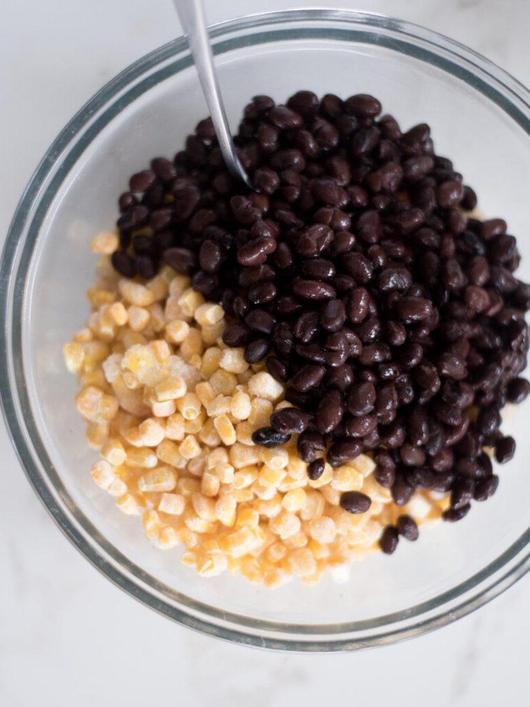 Sformato di Pollo Tex-Mex, Fagioli Neri e Riso 6 Fagioli neri appena aggiunti sopra la miscela di riso e mais in una ciotola, pronti per essere mescolati.