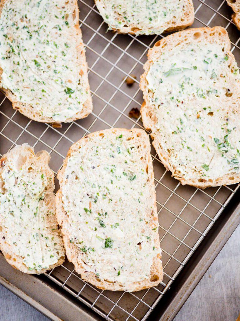 Pane all'aglio fatto in casa con pane a fette 6 miscela di burro spalmata su fette di pane sulla teglia