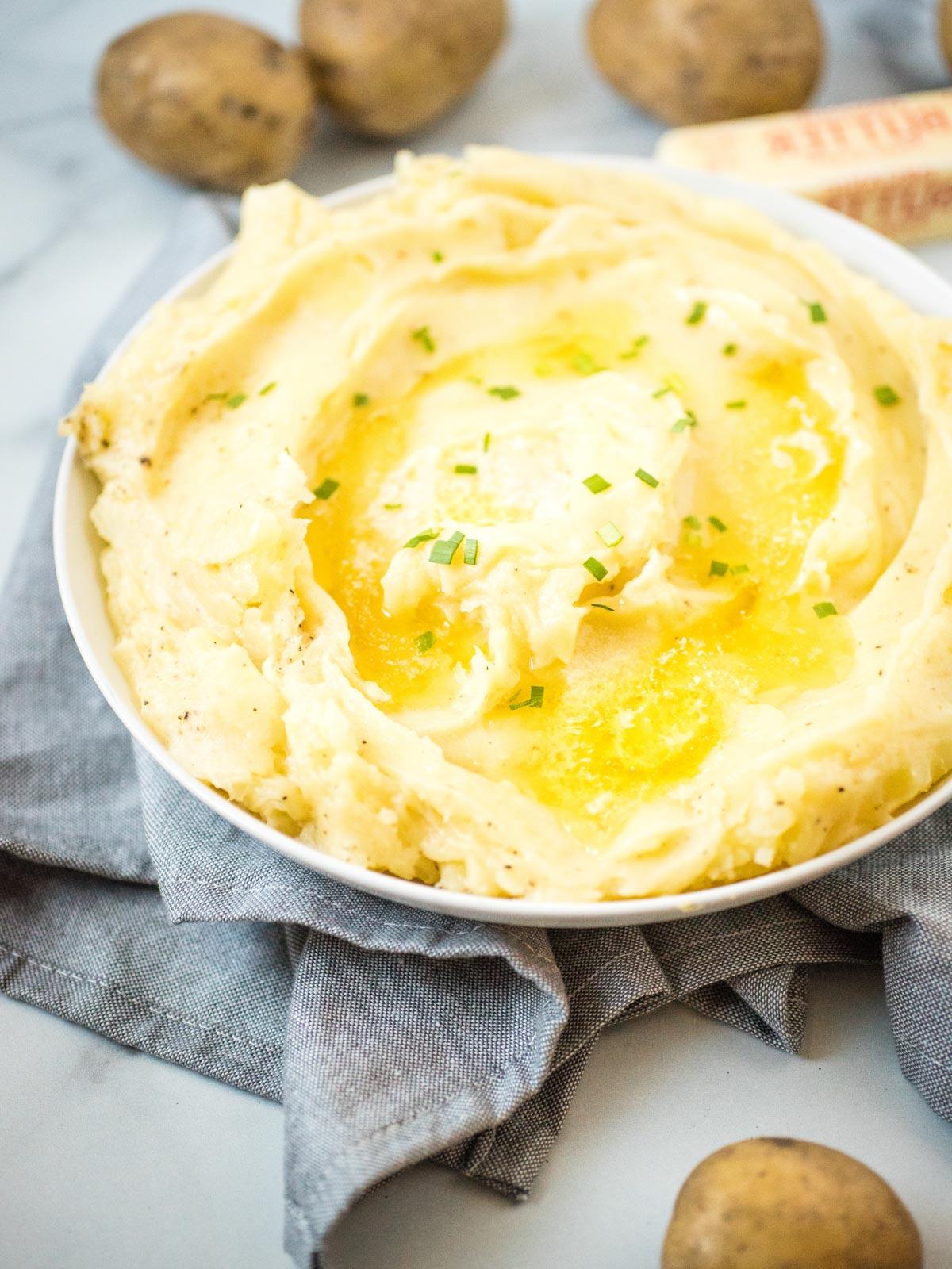 Purè di Patate nella Instant Pot alla Perfezione 7 purè di patate in piatto bianco guarnito con burro fuso ed erba cipollina