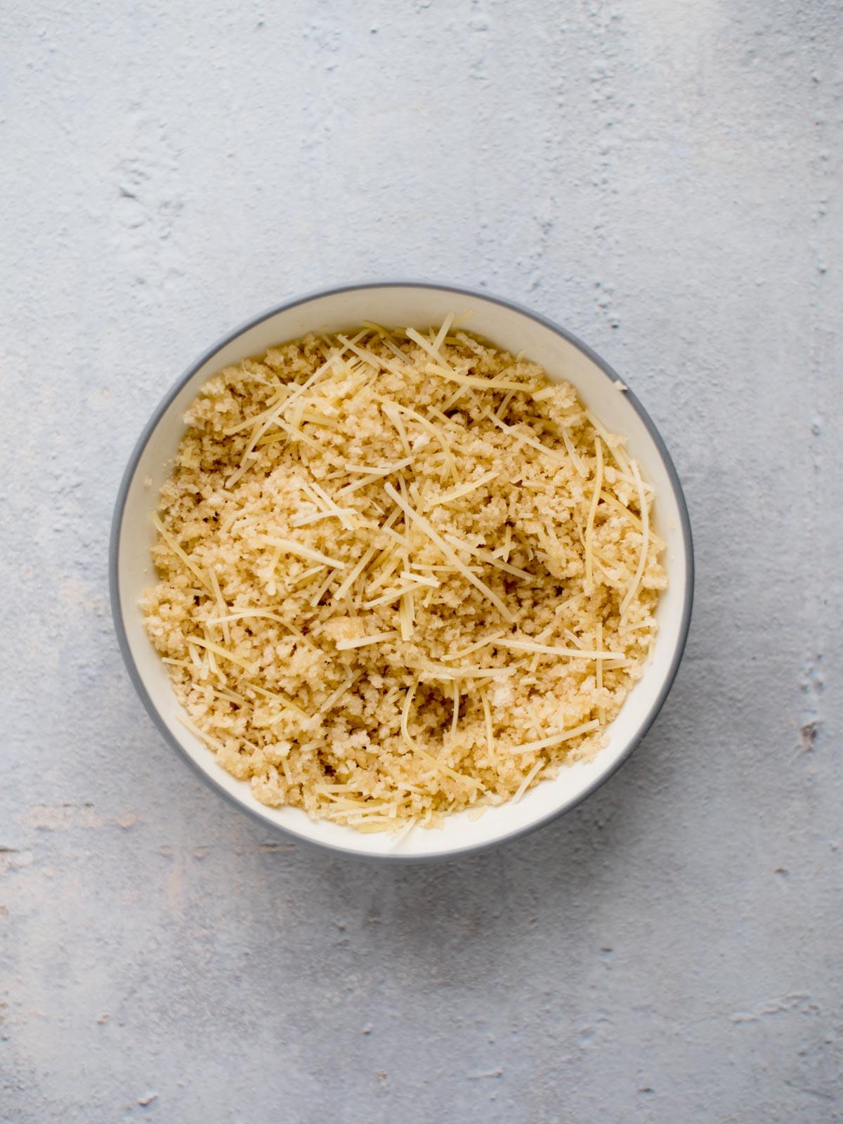 Burro fuso, pangrattato e parmigiano mescolati insieme in una ciotola.