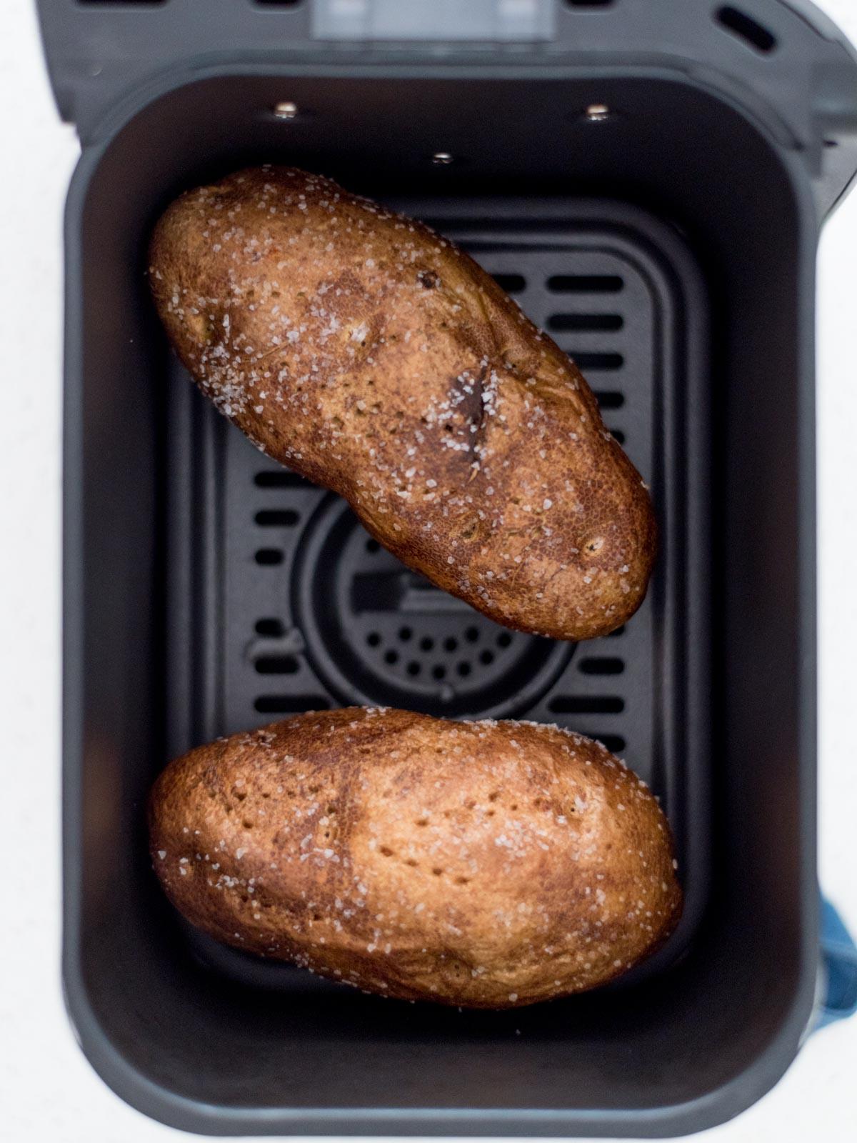 Patate Doppia Cottura in Friggitrice ad Aria 7 Due patate con sale e olio strofinato su di esse in un forno ad aria.