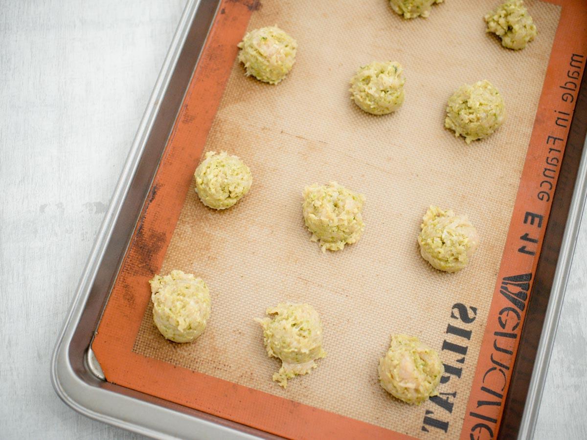 Polpette di Pollo al Pesto 7 polpette di pollo al pesto crude su una teglia foderata con un silpat
