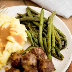 Cosa servire con la Cottage Pie 7 Un contorno di fagiolini verdi arrostiti congelati su un piatto con polpette e purè di patate.