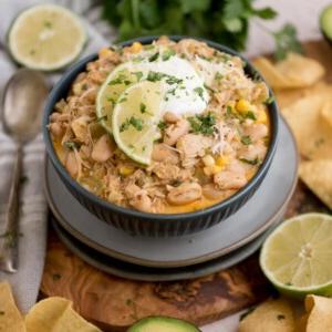 Chili di Pollo Bianco del Sud-Ovest 8 Una ciotola di chili bianco di pollo guarnito con fette di lime e coriandolo, condita con panna acida. Circondato da tortilla chips, metà lime e un cucchiaio.