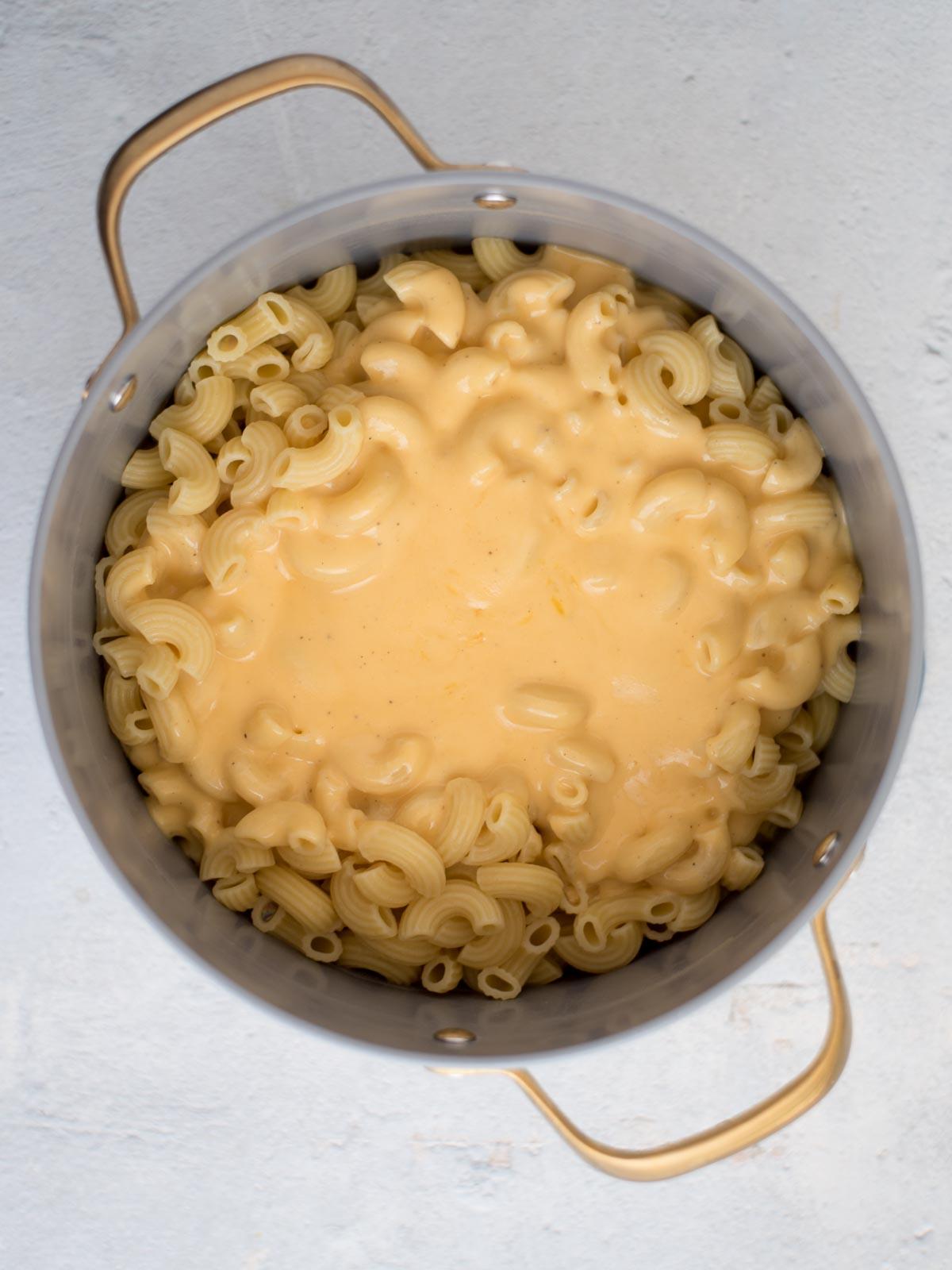 **I Migliori Maccheroni al Forno Super Formaggiosi** 8 Salsa al formaggio versata sopra la pasta cotta in una pentola.